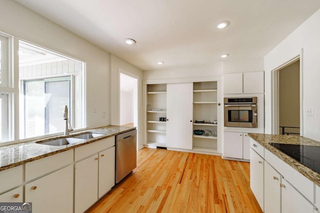 kitchen featuring a sink, light wood-style flooring, white cabinets, appliances with stainless steel finishes, and recessed lighting