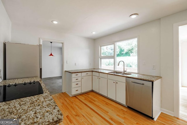 kitchen featuring a sink, light wood-type flooring, white cabinets, appliances with stainless steel finishes, and light stone countertops