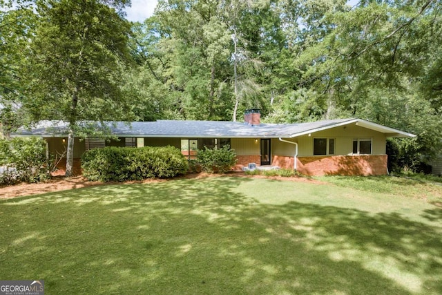 ranch-style house featuring a front lawn, a chimney, and brick siding