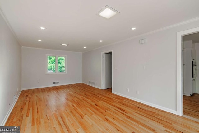 unfurnished room with light wood-type flooring, baseboards, visible vents, and ornamental molding