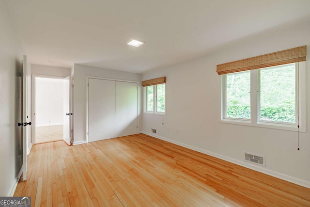 unfurnished bedroom with a closet, visible vents, light wood finished floors, and baseboards