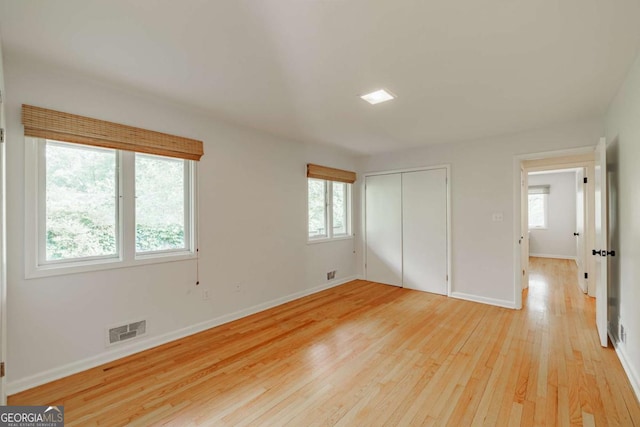 unfurnished bedroom with light wood finished floors, baseboards, visible vents, and a closet