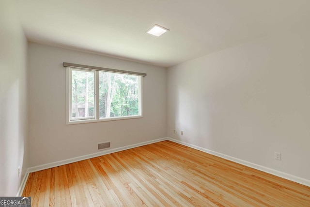 unfurnished room with baseboards, wood finished floors, and visible vents