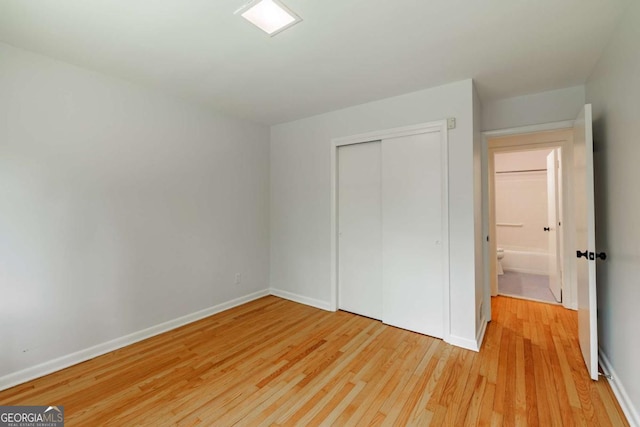 unfurnished bedroom featuring light wood finished floors, baseboards, and a closet