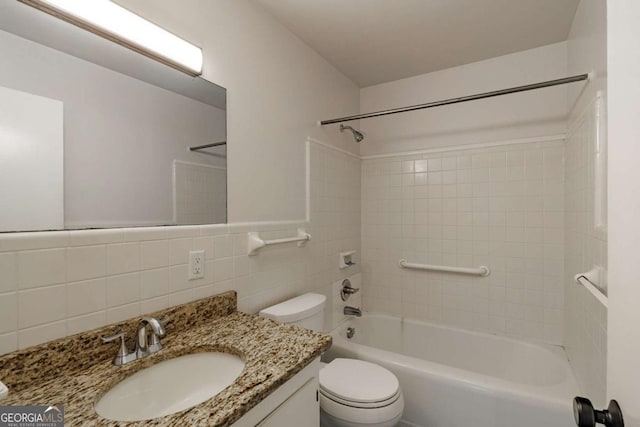 bathroom with tile walls, toilet, vanity, and  shower combination