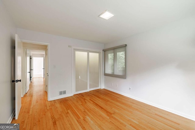 unfurnished bedroom with baseboards, visible vents, light wood finished floors, and a closet