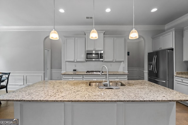 279 Sturry Dr, Mcdonough, GA 30252 - kitchen with arched walkways, a sink, crown molding, a decorative wall, and appliances with stainless steel finishes