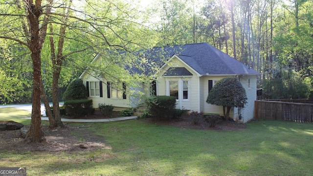 view of front of property with roof with shingles, fence, and a front yard