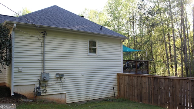view of property exterior with roof with shingles and fence
