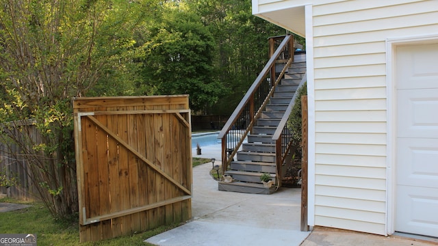 view of gate featuring fence, stairway, and a pool