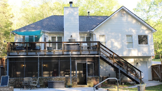rear view of house featuring a chimney, a wooden deck, a sunroom, a shingled roof, and stairs