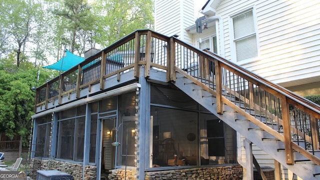 exterior space with a deck, a chimney, stairs, and stone siding