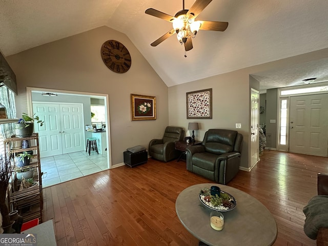 living room with baseboards, wood-type flooring, a ceiling fan, and lofted ceiling