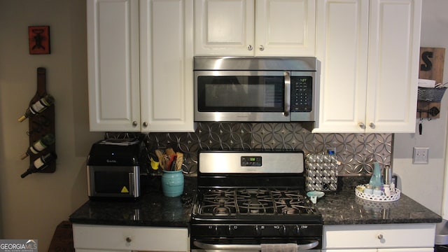 kitchen with white cabinets, appliances with stainless steel finishes, dark stone counters, and tasteful backsplash