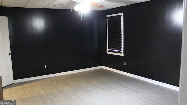 spare room featuring wood finished floors, a ceiling fan, baseboards, and a drop ceiling