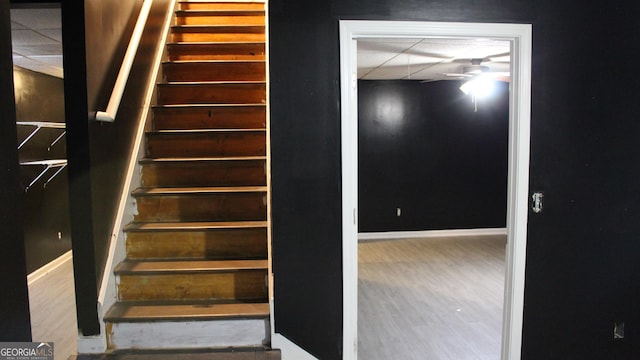 stairs with baseboards, a ceiling fan, and a paneled ceiling