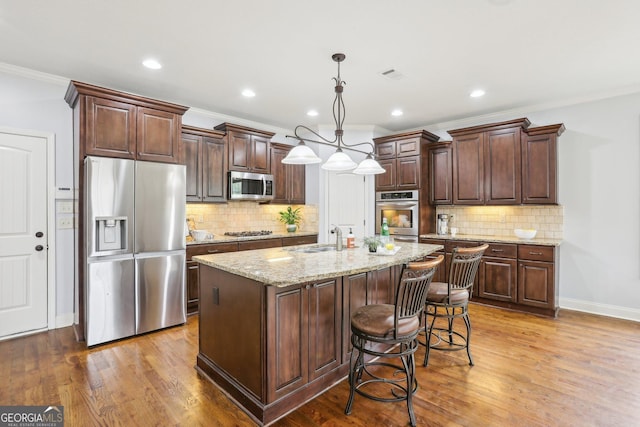 108 Turnberry Trce, Sharpsburg, GA 30277 - kitchen with appliances with stainless steel finishes, ornamental molding, a center island with sink, tasteful backsplash, and wood finished floors