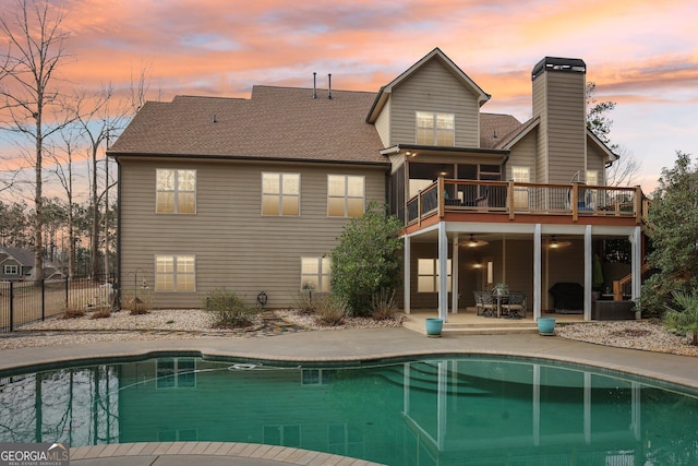 108 Turnberry Trce, Sharpsburg, GA 30277 - back of property at dusk featuring a patio area, an outdoor pool, a ceiling fan, a chimney, and a balcony