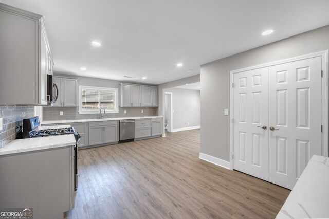 kitchen with a sink, stainless steel appliances, decorative backsplash, and gray cabinets