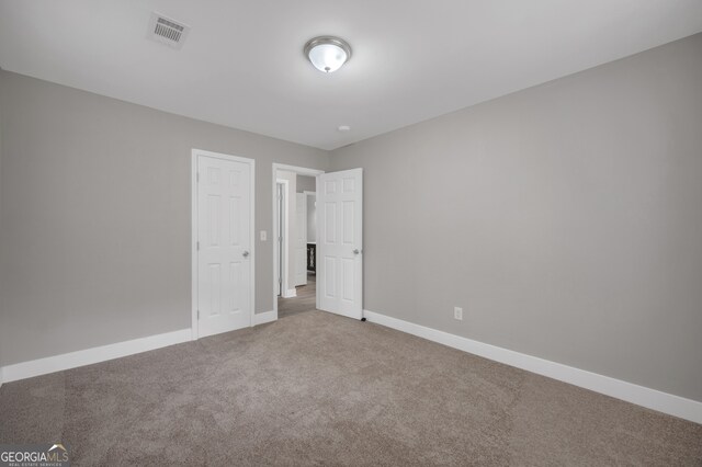 unfurnished bedroom featuring visible vents, carpet, and baseboards