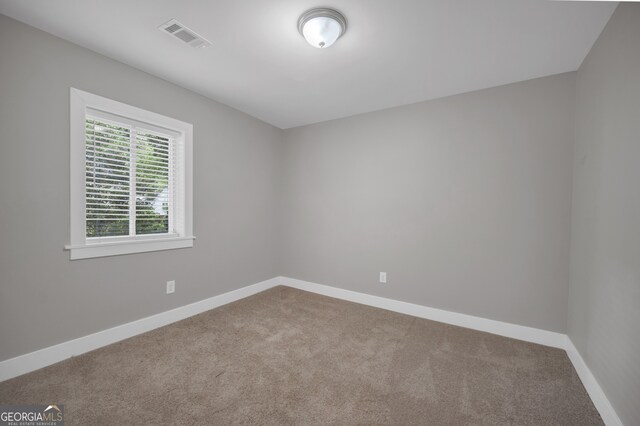 carpeted spare room featuring baseboards and visible vents
