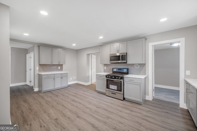 kitchen with gray cabinets, baseboards, stainless steel appliances, and tasteful backsplash