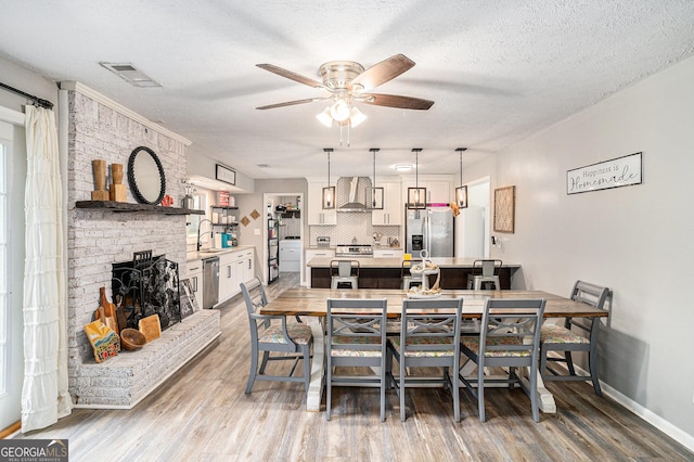 205 Tamea Trl, Covington, GA 30014 - dining space with wood finished floors, a ceiling fan, baseboards, a fireplace, and a textured ceiling