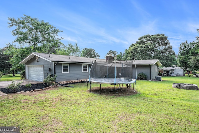 205 Tamea Trl, Covington, GA 30014 - rear view of house with a trampoline, a lawn, central air condition unit, and a chimney