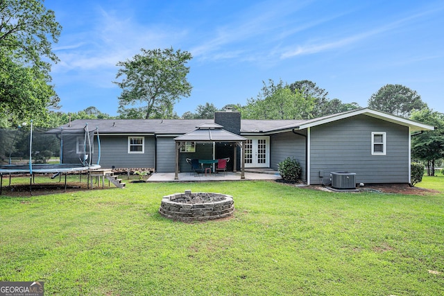 205 Tamea Trl, Covington, GA 30014 - back of house featuring a trampoline, a fire pit, french doors, a patio area, and a chimney
