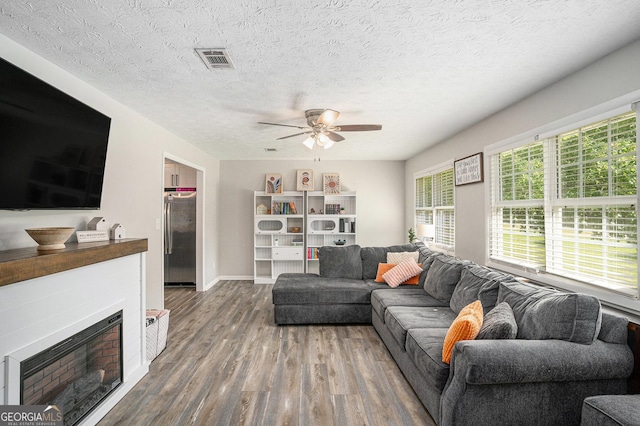 205 Tamea Trl, Covington, GA 30014 - living room featuring ceiling fan, wood finished floors, a textured ceiling, a fireplace, and baseboards