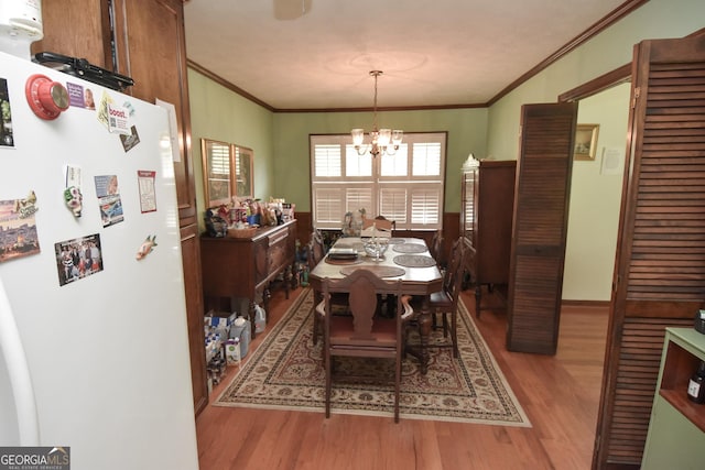 dining room with crown molding, wood finished floors, and a chandelier