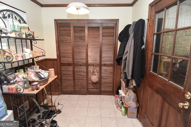 dining area featuring ornamental molding, wooden walls, a wainscoted wall, and light tile patterned floors