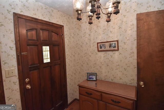 doorway with wood finished floors, a notable chandelier, and wallpapered walls
