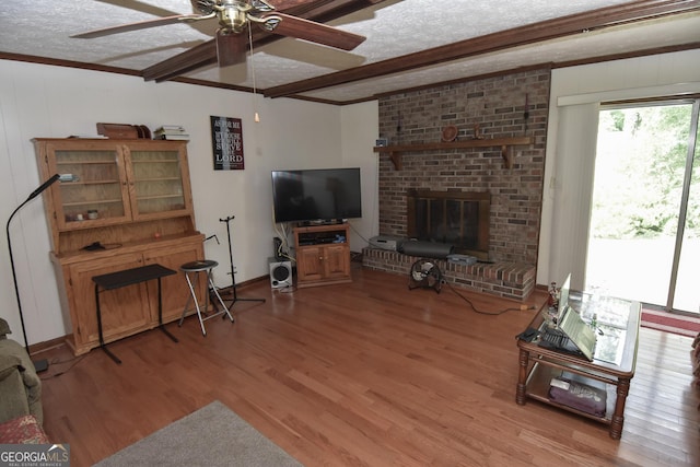 living area featuring a textured ceiling, ceiling fan, wood finished floors, and crown molding