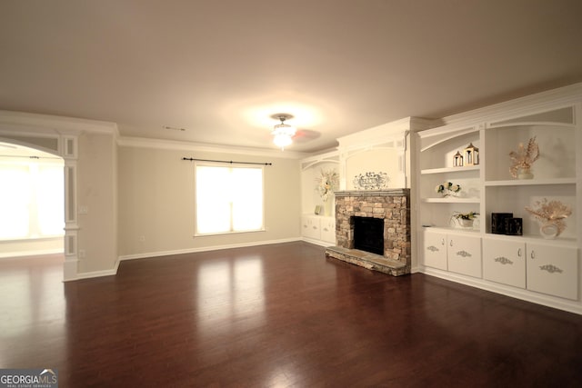 1142 Terrasol Rdg SW, Lilburn, GA 30047 - unfurnished living room with crown molding, arched walkways, a fireplace, baseboards, and dark wood-style flooring