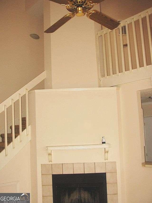 interior details featuring a tiled fireplace and a ceiling fan