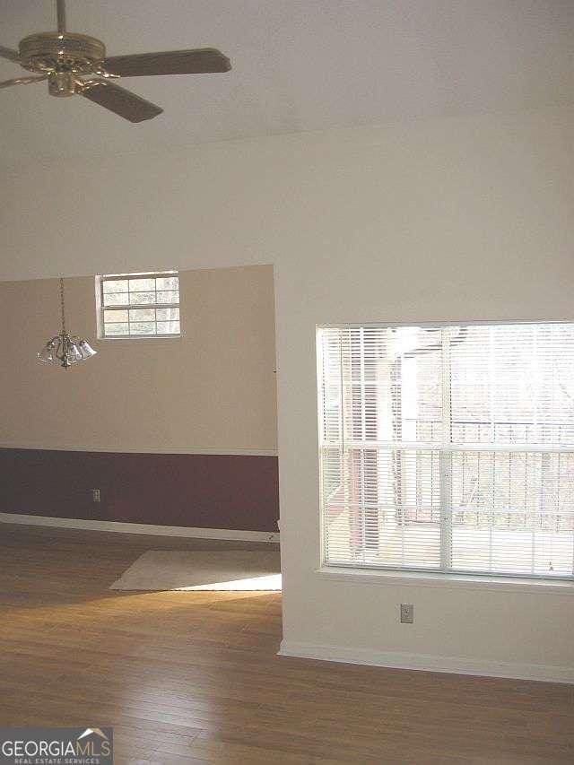 spare room featuring wood finished floors, a ceiling fan, and baseboards