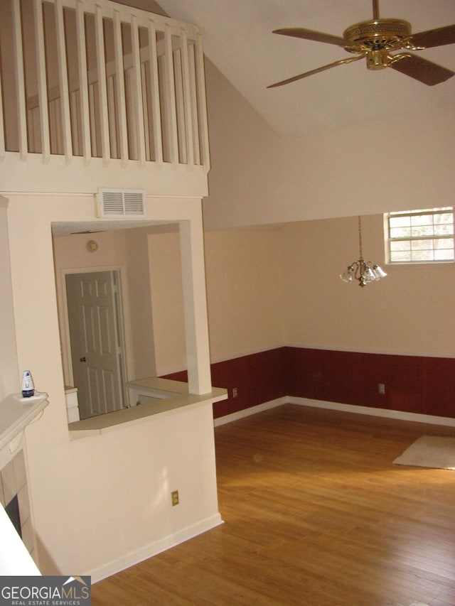 interior space with vaulted ceiling, wood finished floors, visible vents, baseboards, and ceiling fan