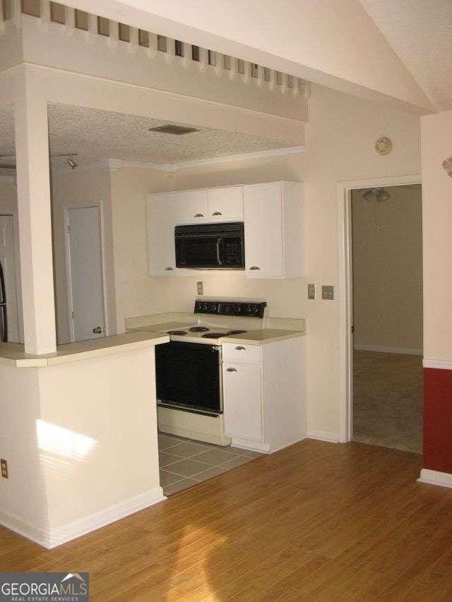 kitchen with white cabinets, black microwave, wood finished floors, and white electric range