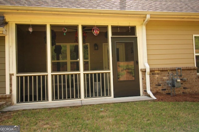 doorway to property featuring brick siding and roof with shingles