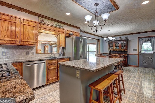171 Wynn Dr, Hampton, GA 30228 - kitchen with stainless steel appliances, a chandelier, brown cabinetry, and ornamental molding