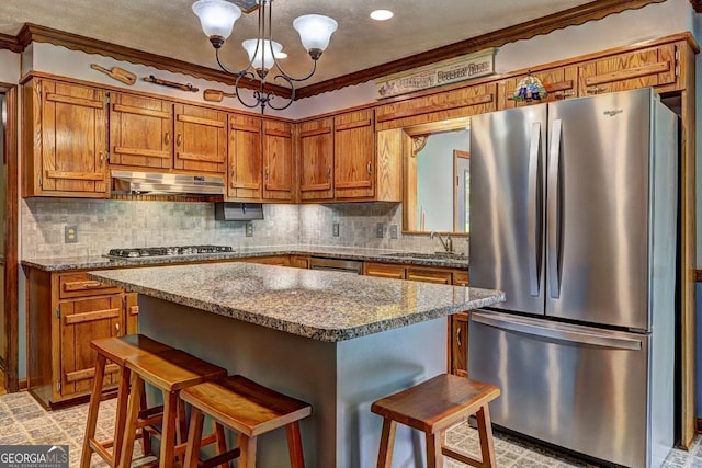 171 Wynn Dr, Hampton, GA 30228 - kitchen with crown molding, stainless steel appliances, brown cabinets, and under cabinet range hood