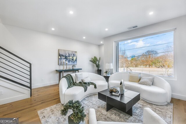 living room featuring visible vents, wood finished floors, baseboards, stairway, and recessed lighting