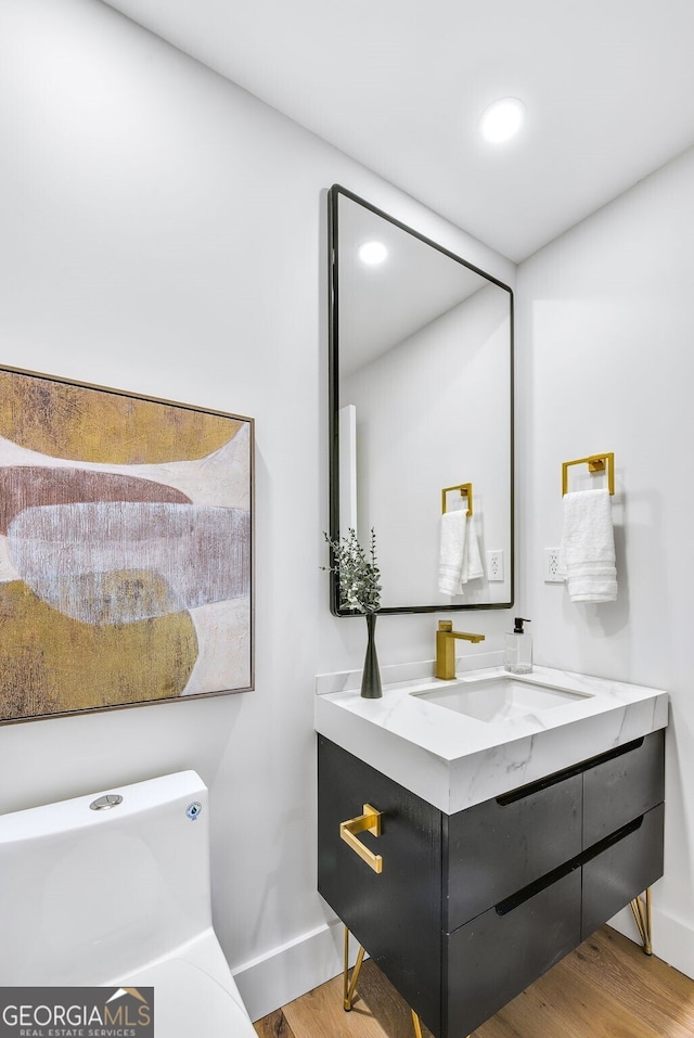 bathroom featuring baseboards, vanity, recessed lighting, and wood finished floors