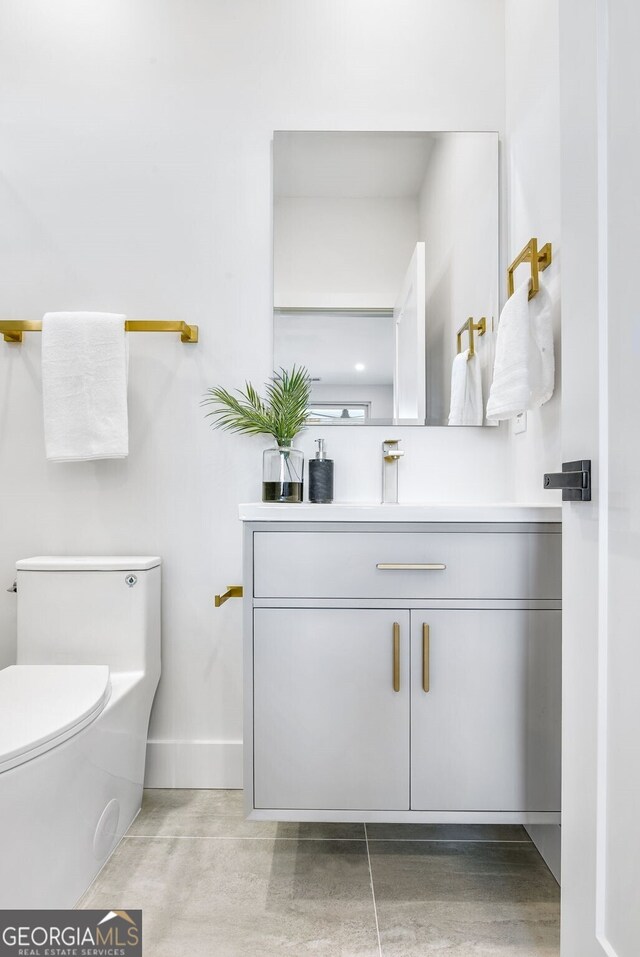 bathroom featuring toilet, baseboards, and vanity