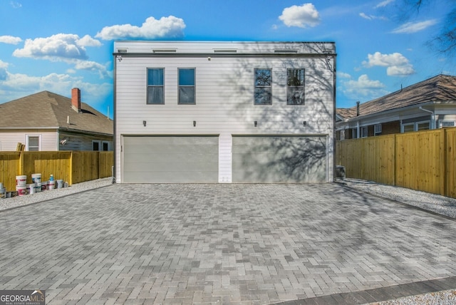 exterior space featuring decorative driveway, a garage, and fence