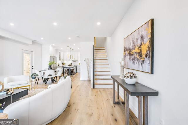 living area with light wood-type flooring, recessed lighting, and stairs