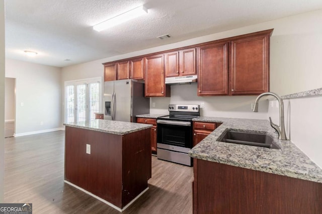 kitchen with a sink, wood finished floors, visible vents, under cabinet range hood, and appliances with stainless steel finishes