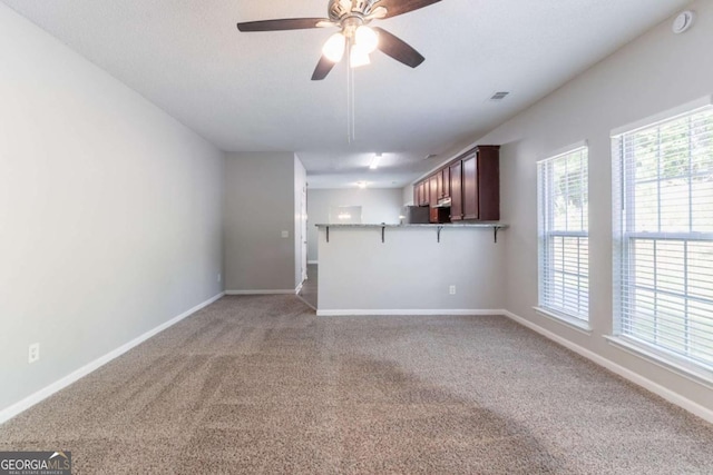 unfurnished living room featuring baseboards, light carpet, visible vents, and ceiling fan