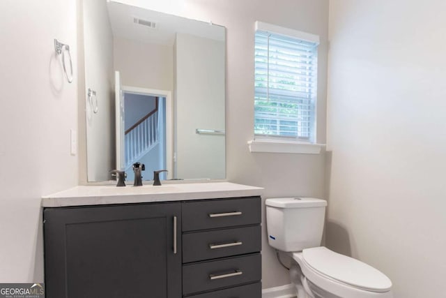 bathroom with toilet, visible vents, baseboards, and vanity